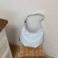 Detail showing the light blue leather hobo bag with adjustable silver buckle strap on a stool - Blue