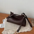 Detail view of smooth dark brown leather bag with fold design and gold metal buckle - Brown