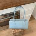 Detalle del bolso baguette azul cielo con asas finas y textura de cuero mate estilo retro - Azul