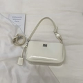 Detalle del bolso baguette blanco crema con cierre giratorio plateado y doble correa - Blanco