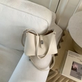 Cream hobo shoulder bag in pebble grain leather with silver rotary buckle on a sofa - White Without Pendant