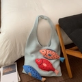 Détail du sac cabas tricoté bleu clair avec poissons 3D colorés sur linge blanc - Bleu