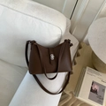 Dark brown lychee pattern leather shoulder bag with silver turn-lock on a sofa - Coffee without Pendant