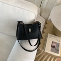 Chic black lychee texture leather bucket bag with silver geometric lock on a white sofa - Black without Pendant