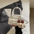 Detail der weißen Boston-Tasche mit Schleifentasche, Bärenanhänger und Handgriffen - Mit Anhänger / Gebrochenes Weiß