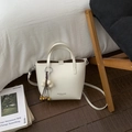 Close-up of cream white bucket bag with leather texture and floral charm detail - White with Pendant