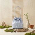 Detailed close-up of a blue floral bucket bag with bow detail on a Zen stone pedestal - Light Blue