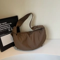 Detailed macro view of deep brown nylon dumpling bag with silver metal eyelets and drawstring - Coffee