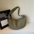 Detail of olive green crescent dumpling bag showing soft nylon texture and wide strap - Green