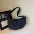 Detail view of large dark blue nylon dumpling bag with metal ring and wide shoulder strap - Blue