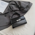 Glänzende schwarze Lederhandtasche mit Silberverschluss auf einem grauen Sakko - Schwarz (Ohne Anhänger)