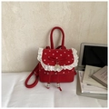 Detalle de mini mochila roja de lunares con ribete de encaje, lazo y colgante de corazón - Rojo