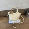 Dettaglio borsa a secchiello in pelle crema con ciondolo a cavallo e tracolla intrecciata - Grigio Chiaro