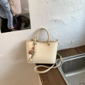 Close-up of cream leather square bag with soft texture and cute plush mushroom charm - With Charm / White