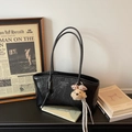 Dettaglio della borsa tote in pelle nera a pieghe con charm a cane e nappa argento - Nero con ciondolo