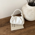 Vue détaillée du sac nuage plissé blanc sur une table en bois avec décor élégant - Blanc