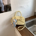 Détail du sac Boston crème avec texture cuir souple et charmant pendentif ours - Jaune avec Pendentif