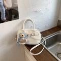 Détail du sac polochon rétro blanc cassé avec boucles en argent et un charmant petit ours - Blanc avec pendentif