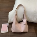 Detailopname van roze leren tote tas met zilveren metalen studs en brede schouderband - Roze