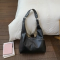 Detail van zwarte hobo tas van kunstleer met zilveren oogjes en decoratieve klinknagels - Zwart