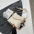 Beige bucket bag with woven handle and plush rabbit charm on a gray blazer - With Pendant / White
