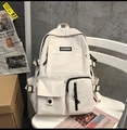 Dettaglio dello zaino scolastico in nylon crema con design multitasche su una sedia - Bianco (Senza Ciondolo)