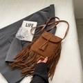 Bruine suède crossbody tas met franjes gepresenteerd op een stijlvolle grijze blazer - Khaki