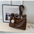Detail der weichen dunkelbraunen Lederschultertasche mit Gurt und Plüsch-Anhänger - Mit Anhänger / Braun
