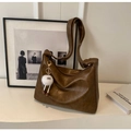 Detaillierte Nahaufnahme der braunen Vintage-Ledertasche mit niedlichem Plüschmonster-Anhänger - Mit Anhänger / Sandfarben