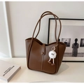 Vue détaillée du sac cabas marron en cuir avec un charmant monstre en peluche blanc - Avec Pendentif / Marron