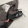 Bolso de hombro en cuero negro brillante con detalle de cordones sobre blazer gris - Negro