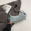 Bolso baguette de mezclilla azul claro con correa ajustable sobre una chaqueta gris - Azul
