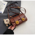 Macro shot of dark brown Boston bag with golden ring locks and cute lamb charm - Brown