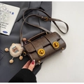 Detailed close-up of retro brown pillow bag with gold twist locks and lion charm decor - Coffee