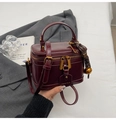 Vintage bordeauxrote Kofferhandtasche aus glänzendem Kunstleder mit goldenem Anhänger - Burgunderrot