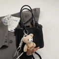 Chic black lychee texture bucket bag featuring a unique knotted handle and teddy bear charm - With Plush Bear Pendant / Black