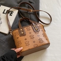 Retro braune geprägte Eimertasche mit verstellbarem Gurt auf grauem Stoffhintergrund - Braun - Ohne Anhänger