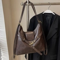 Deep brown vintage leather tote bag with gold buckle displayed on a black blazer - Coffee