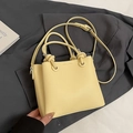Bolso tipo cubo en cuero amarillo pálido con nudo en el asa y correa sobre una chaqueta - Sin colgante / Amarillo