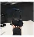 Close-up of black leather shell bag with gold chain strap in minimalist modern setting - Black