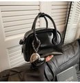 Close-up of black glossy bowling handbag with heart charm and logo embossing - With Charm / Black