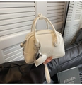 Detail of white oil wax leather handbag featuring heart-shaped metal charm and embossed text - With Charm / White
