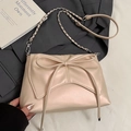 Chic beige bow shoulder bag with silver chain strap shown on dark grey suit jacket - Pink