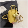 Detail of yellow lychee leather mini bowling bag with cute plush puppy charm accessory - Yellow with Pendant