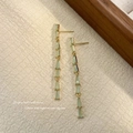 Elegant long tassel drop earrings with light green gemstones and gold metallic chains - Cyan