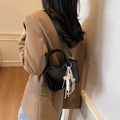 Bolso de mano de charol negro con colgante de oso, mostrado por modelo en blazer café - Con Colgante / Negro