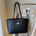 Classic black tote bag with lychee texture and metallic detail hanging with a coat - Black - Without Pendant