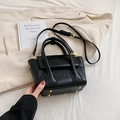 Elegant black leather bucket bag with dual handles and gold protective feet on base - Black