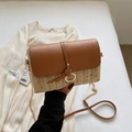 Sac bandoulière en paille avec rabat en cuir marron et chaîne dorée tenu à la main - Blanc Cassé
