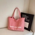 Pink canvas tote bag with Love you Baby slogan print in a minimalist studio setting - Pink